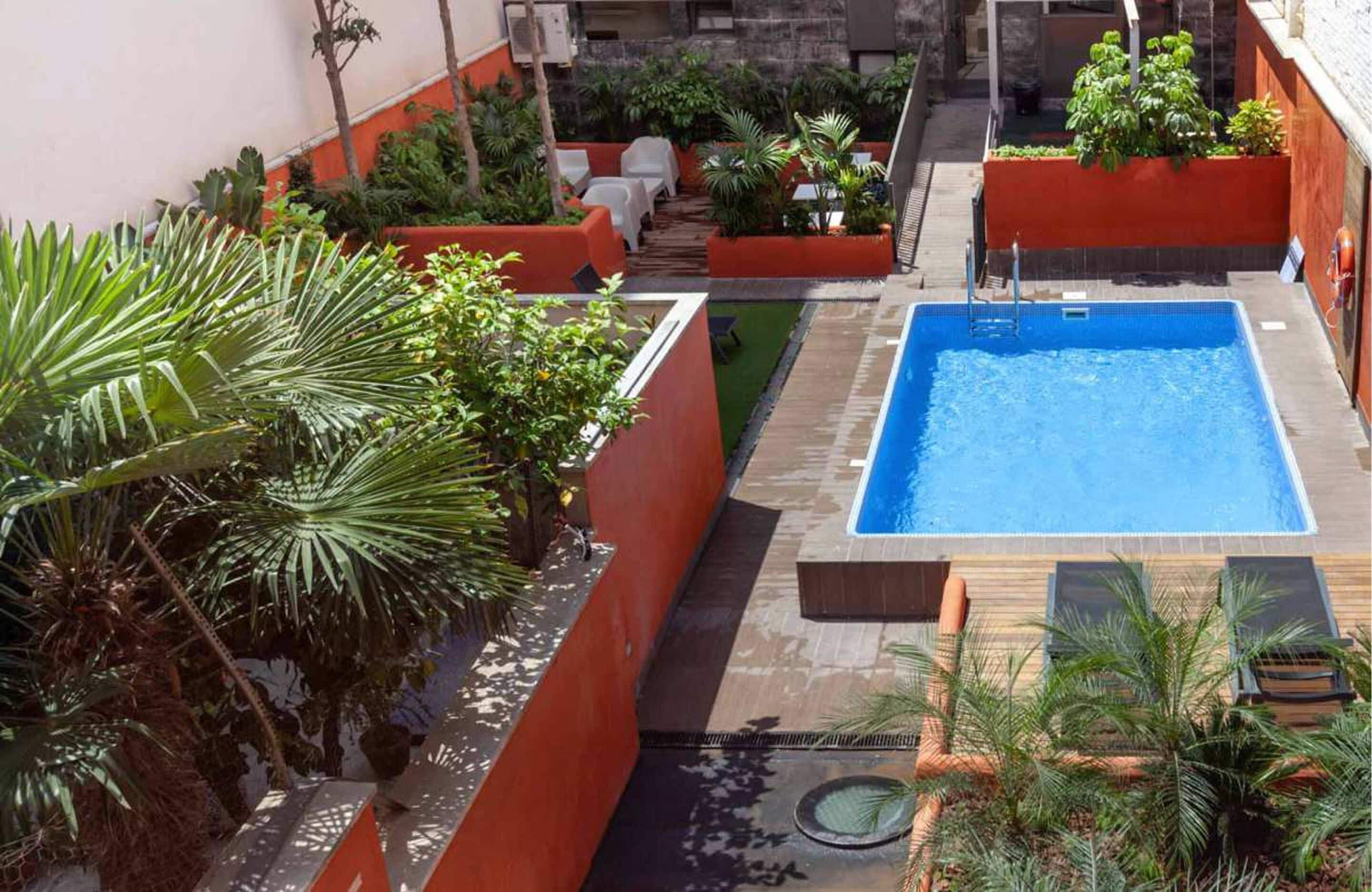 Piscina no terraço com áreas verdes e espaços para sentar ao redor.