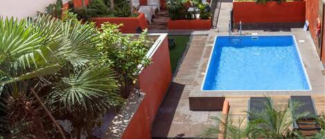 Piscina no terraço com áreas verdes e espaços para sentar ao redor.