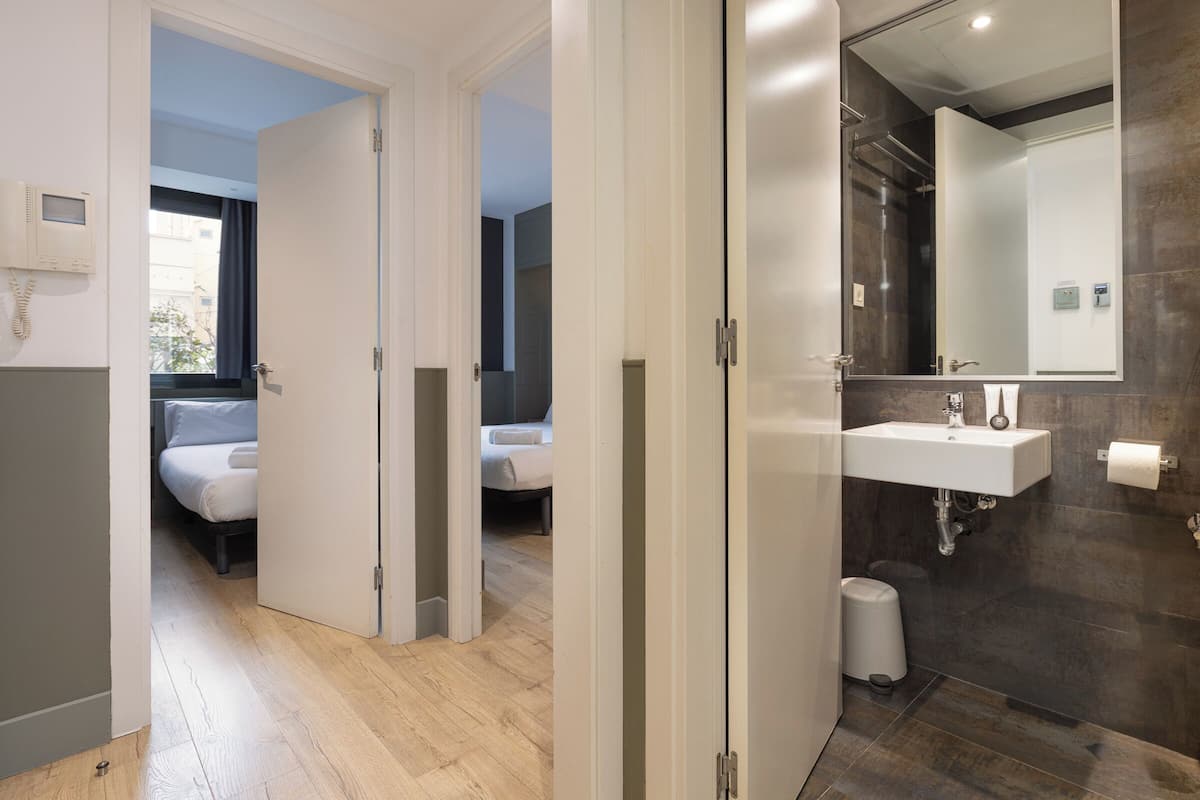 Una habitación de hotel moderna con suelo de madera, un espejo grande, un lavamanos y un inodoro.