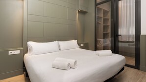 Un dormitorio moderno con una cama grande, un armario empotrado y un ventanal corredero que da a un balcón.