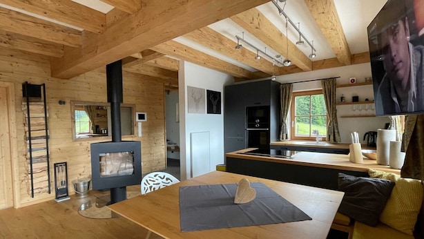 A cozy cabin interior with a wooden interior, a fireplace, a kitchen area, and a dining space. - Mankerl Hut, Austria (Schönberg-Lachtal)