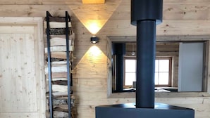 A room with a wood-burning stove, a ladder, and a window. - Mankerl Hut, Austria (Schönberg-Lachtal)