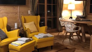 A cozy room with yellow armchairs, a wooden dining table, and a lamp. - Mankerl Hut, Austria (Schönberg-Lachtal)