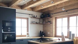 A modern kitchen with a central island, wooden beams, and built-in appliances. - Mankerl Hut, Austria (Schönberg-Lachtal)