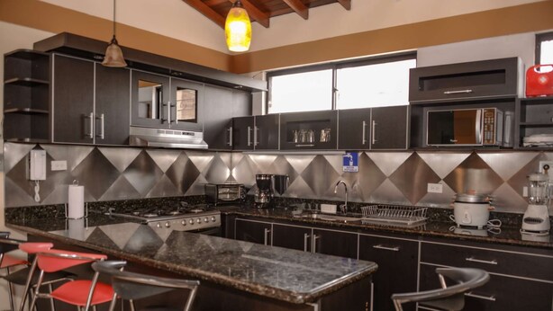 Una cocina moderna con una isla central, electrodomésticos de acero inoxidable y taburetes de bar.