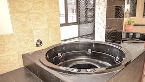 Un baño moderno con una bañera independiente, paredes con azulejos y un espejo decorativo.