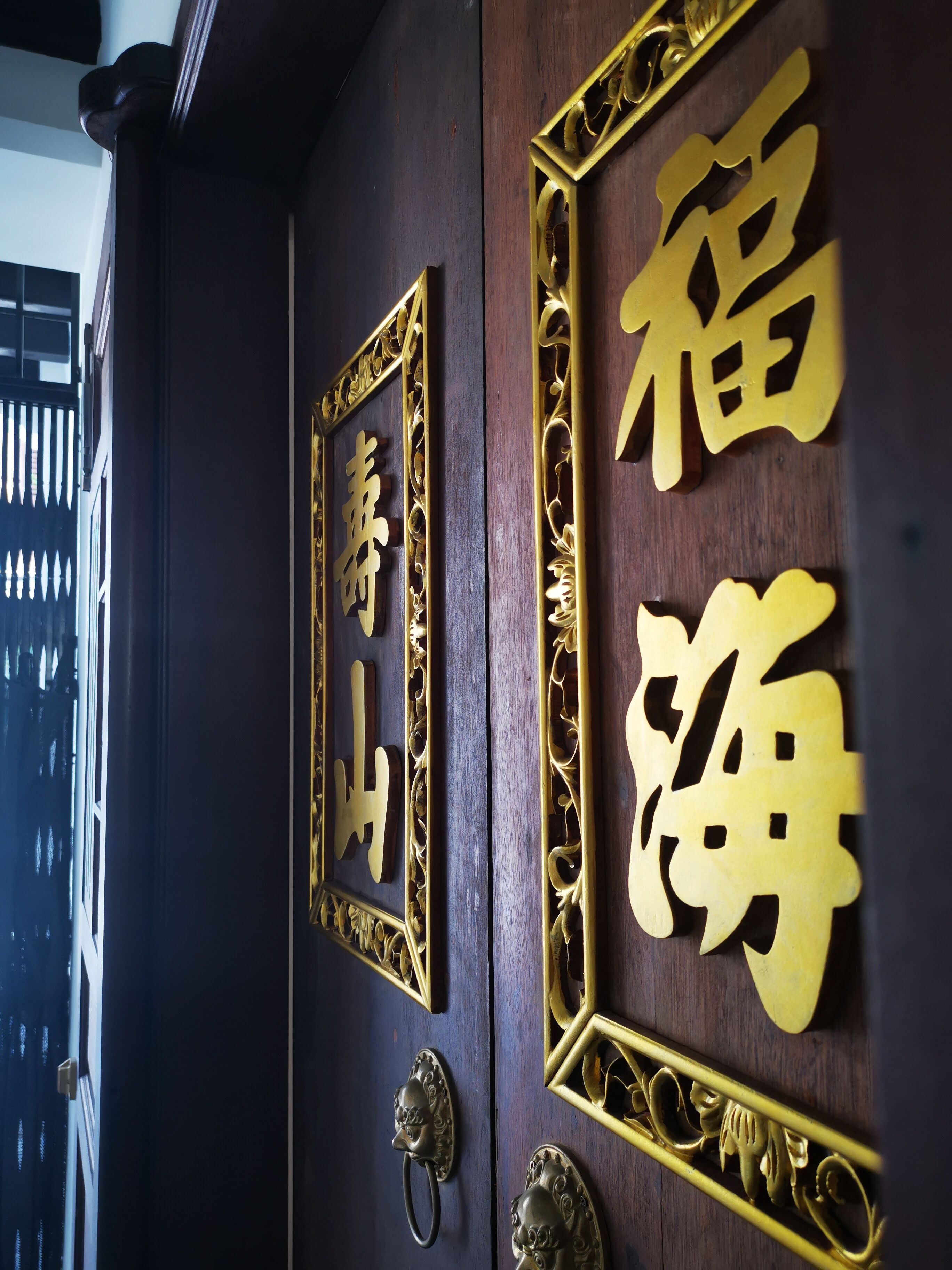 A wooden door with golden Chinese characters and ornate metalwork.