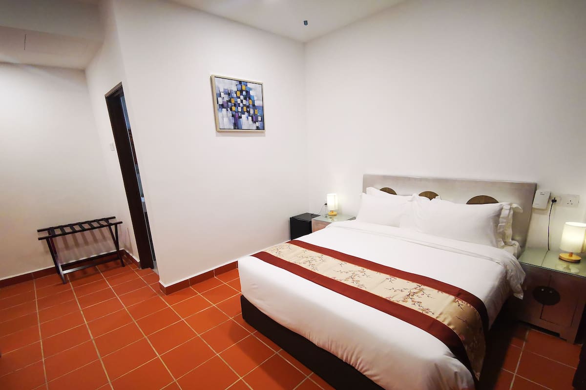 Ein Hotelzimmer mit Bett, Nachttischen, einer Lampe und einem an der Wand hängenden Bild.