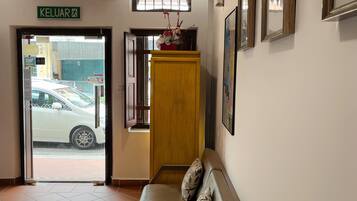 A reception area with a sofa, a wooden cabinet, and framed pictures on the wall.