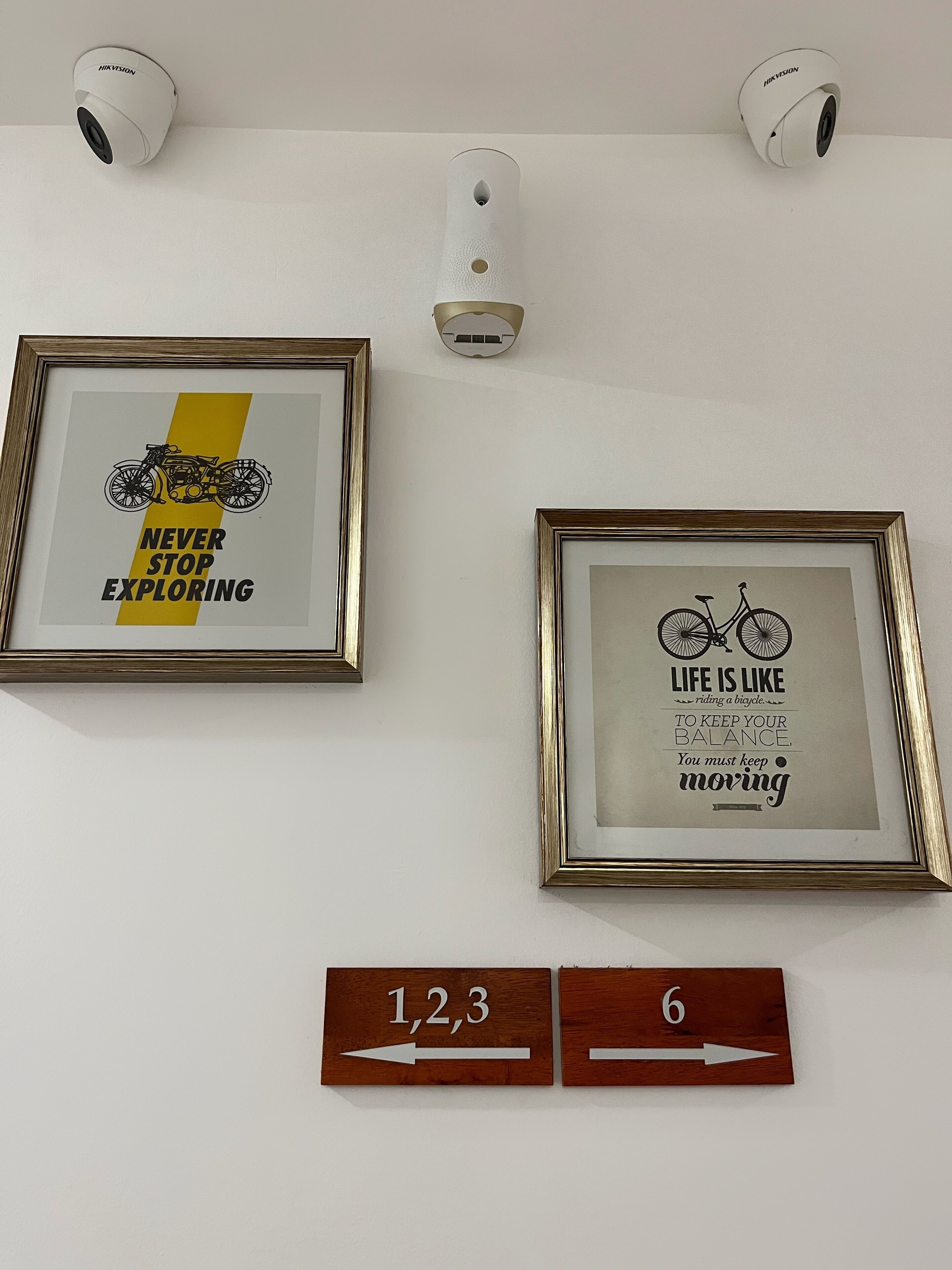 Two framed motivational posters, a wall-mounted security camera, and directional signs.