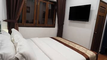 A bedroom with a bed, curtains, a television, and a door.