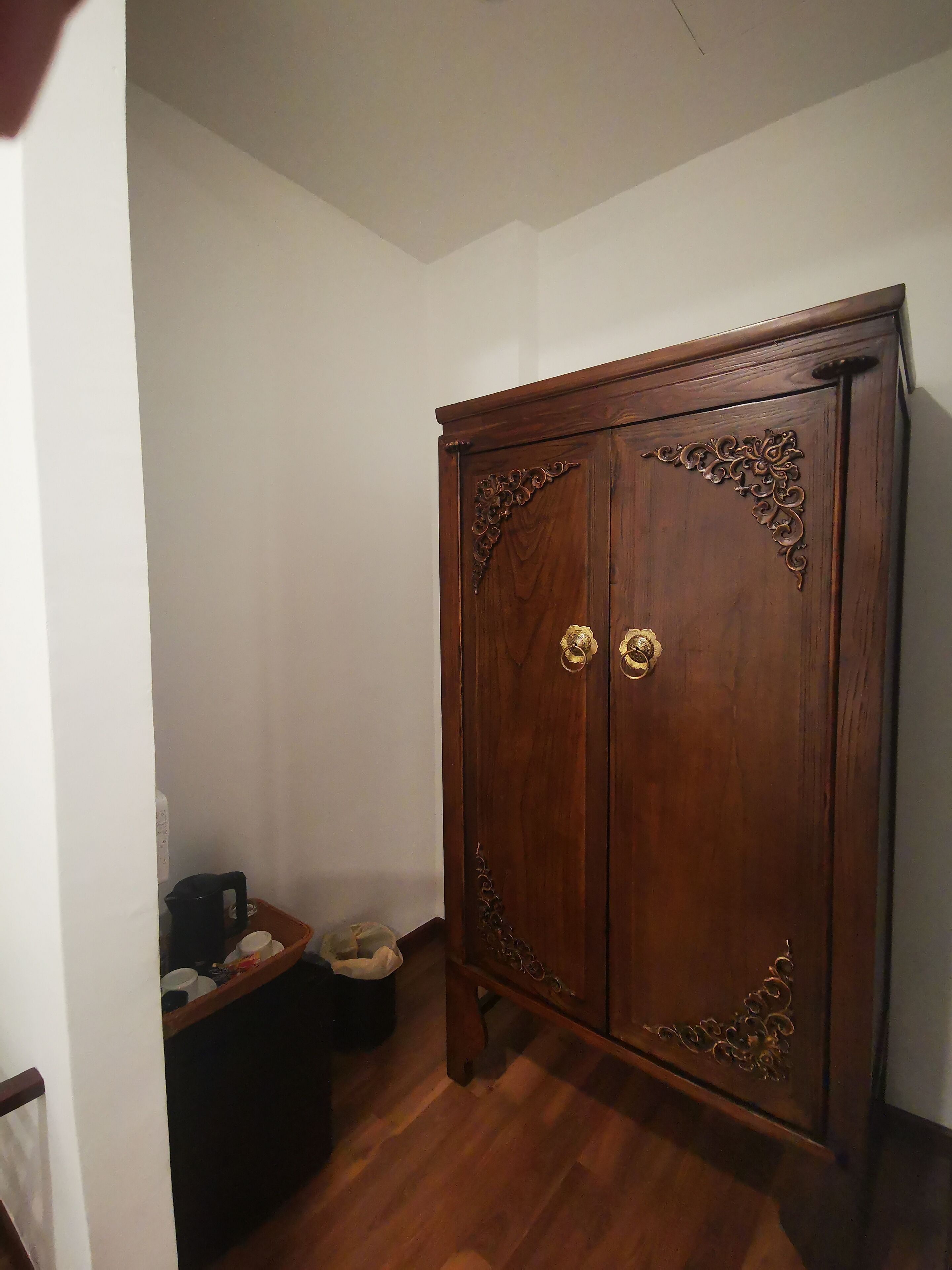 A wooden wardrobe with ornate carvings and brass handles.