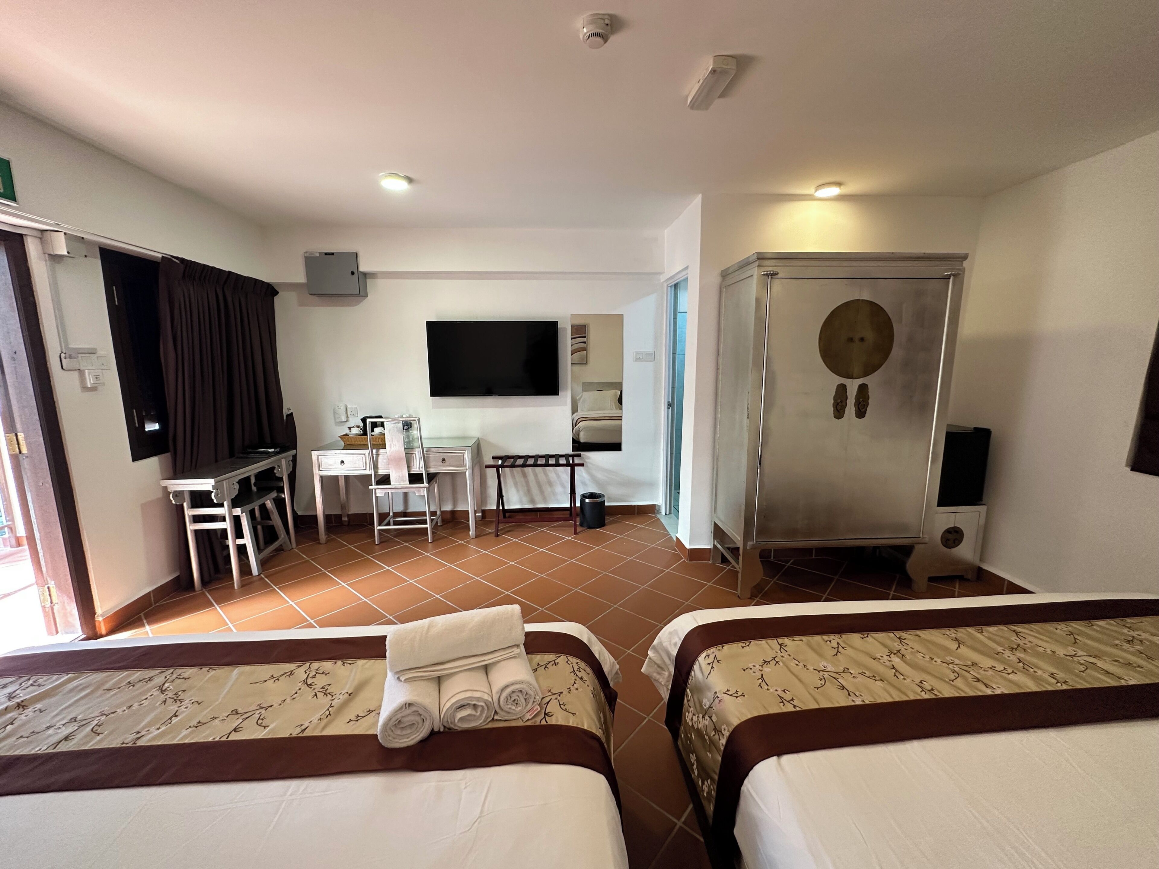 Une chambre d’hôtel avec deux lits, un bureau, une chaise, une télévision et un minibar.