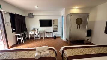Une chambre d’hôtel avec deux lits, un bureau, une chaise, une télévision et un minibar.
