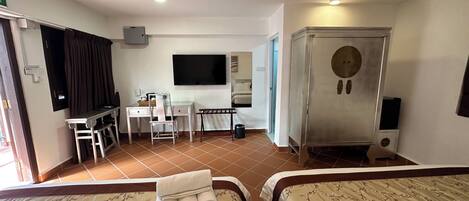 A hotel room with two beds, a desk, a chair, a television, and a minibar.