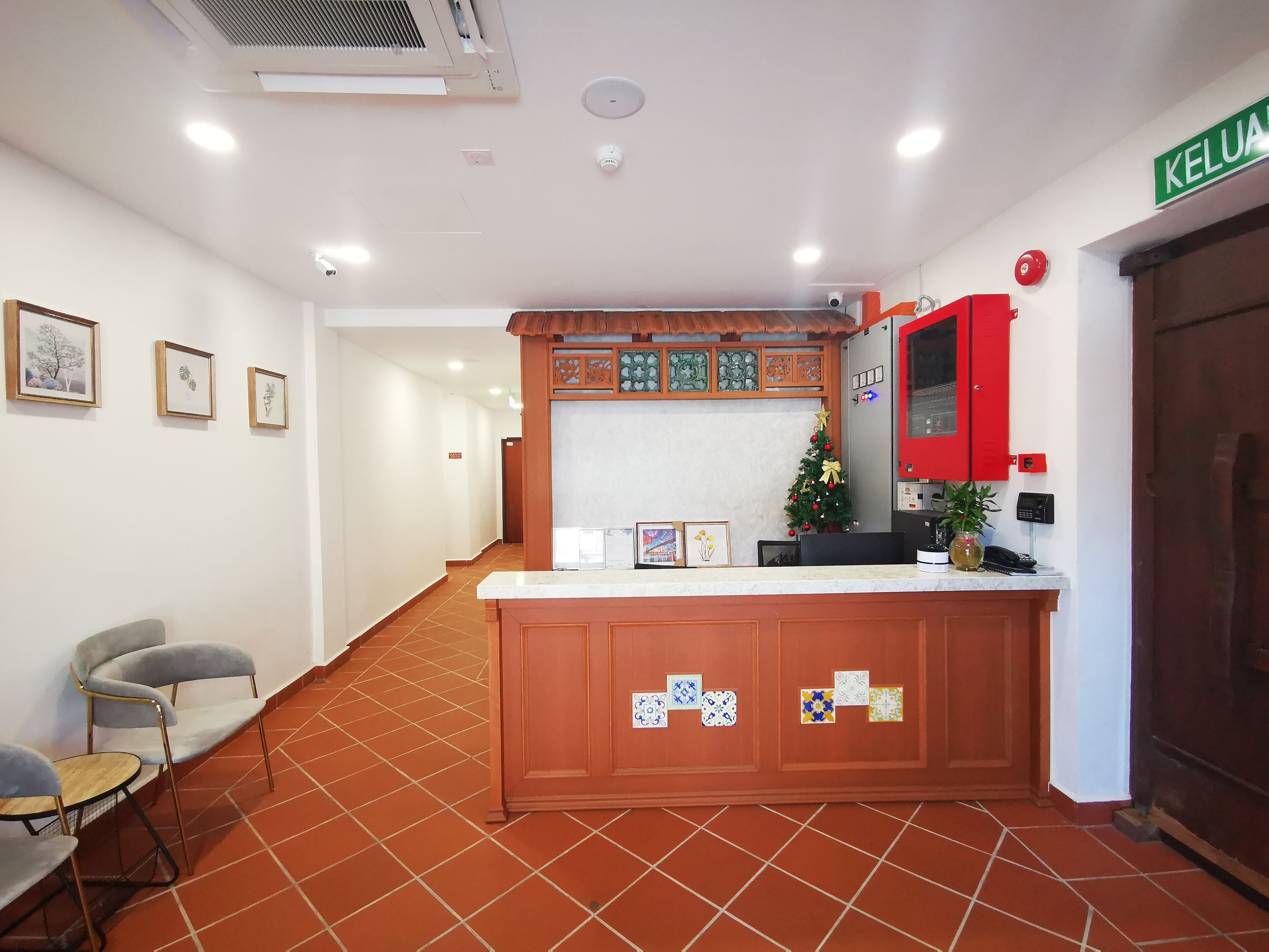 A reception area with a wooden counter, framed pictures on the wall, a small Christmas tree, and a red telephone.