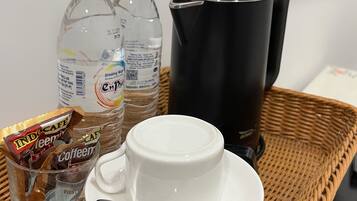 Una safata amb una tassa blanca, una cullera, dues amples d'aigua i un paquet de dosi de cafè.