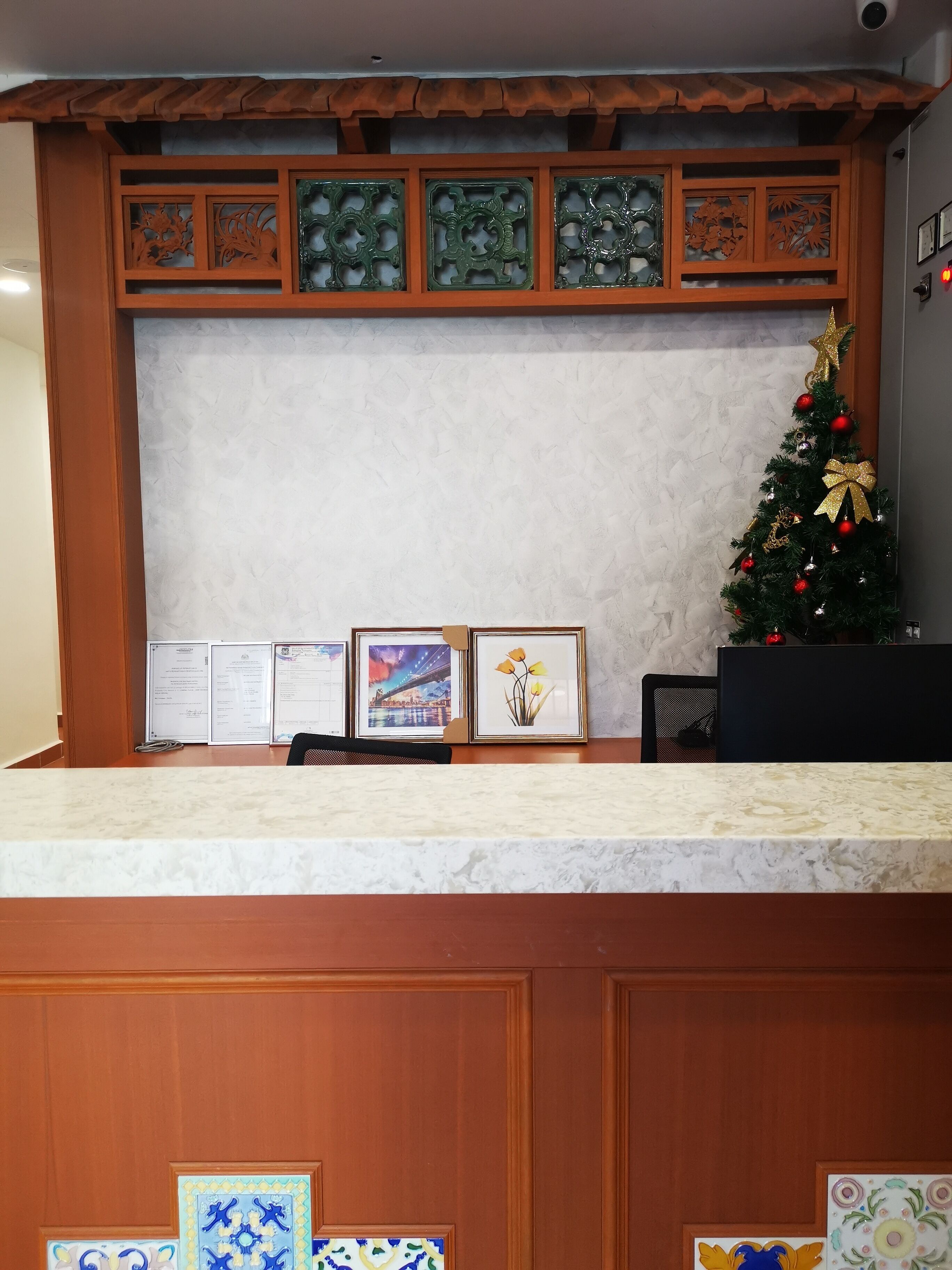 A reception desk with a marble top, framed certificates, and a decorated Christmas tree.