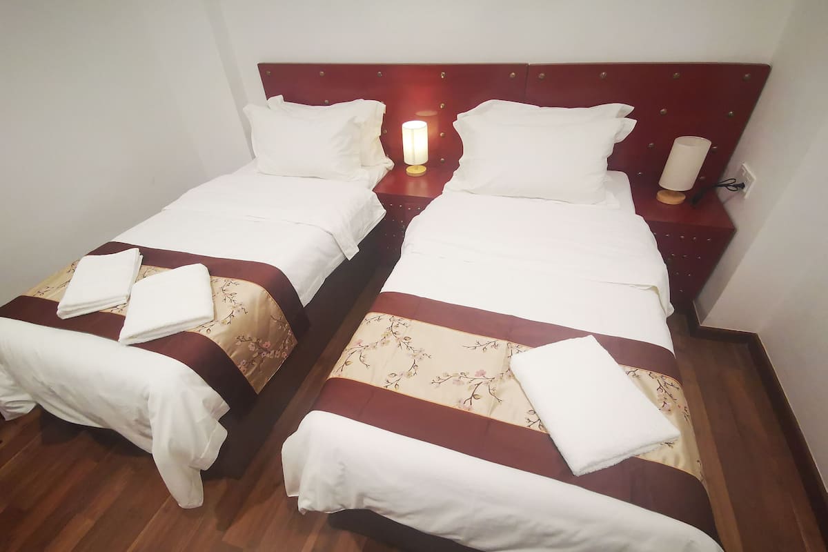 Two single beds with wooden headboards, white linens, and floral-patterned bedspreads.
