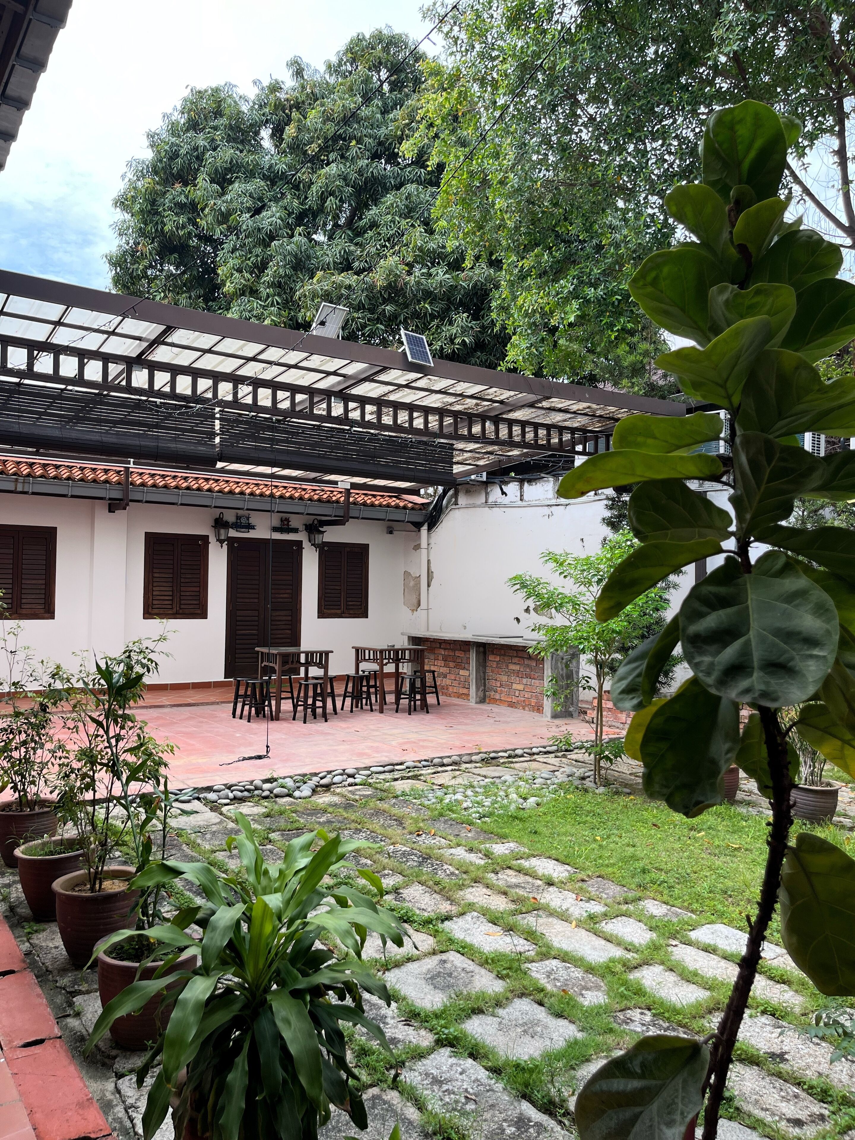 A traditional building with a tiled roof, a courtyard with stone paving, and potted plants.