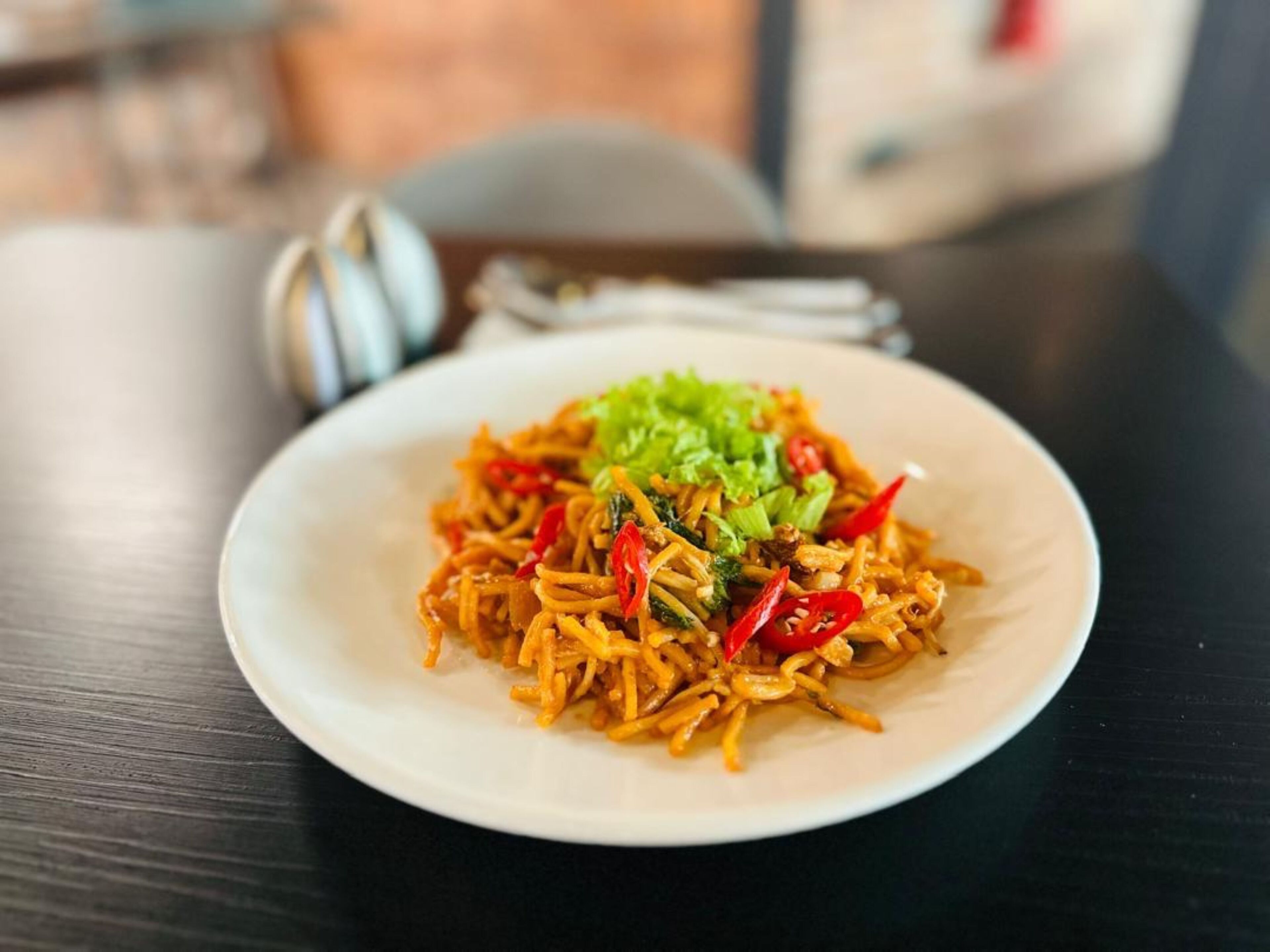 A plate of stir-fried noodles with vegetables on a white plate.