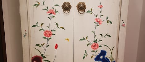 A white cabinet with floral designs and two brass handles.