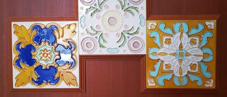 Three framed decorative tiles on a wooden wall.