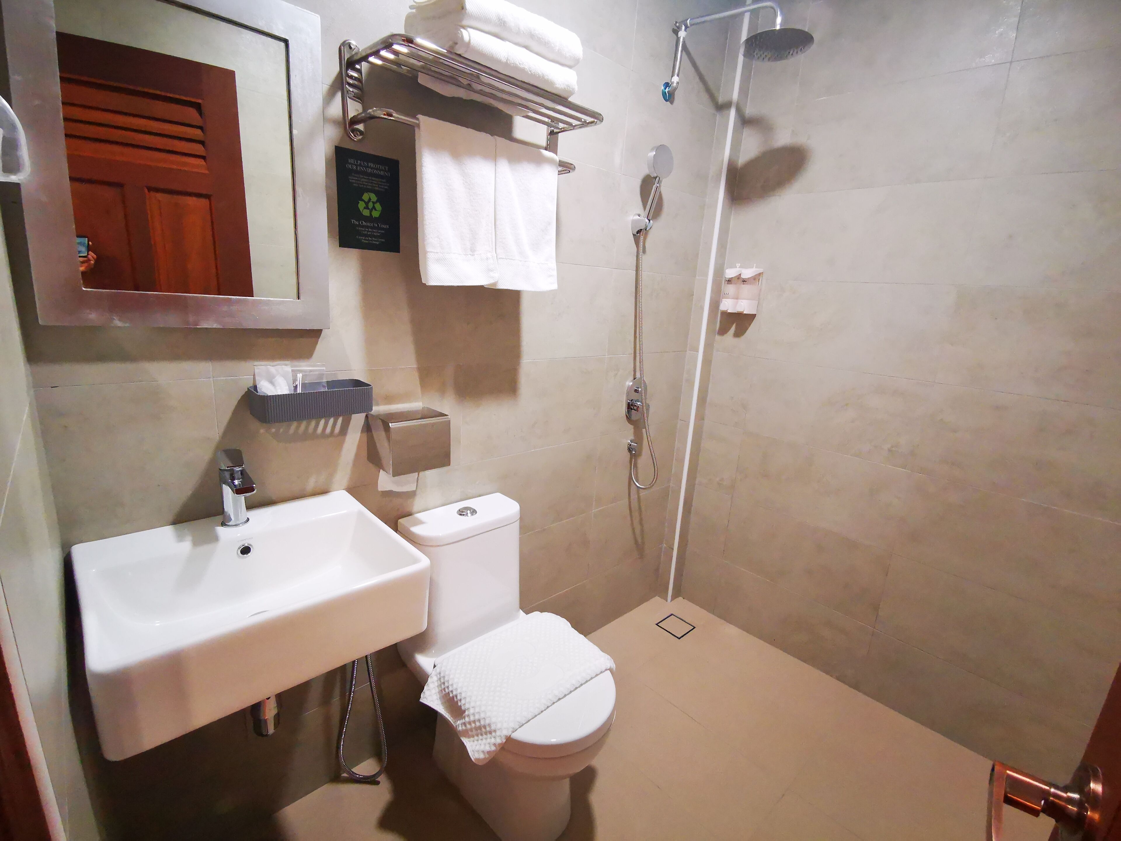 Une salle de bain avec un lavabo, des toilettes et une douche. Il y a un porte-serviettes au-dessus du lavabo et un panneau sur le mur.