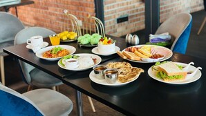 A dining table set with various dishes including rice, bread, and a salad, in a room with brick walls and modern chairs. - Mclane Boutique Hotel (George Town)