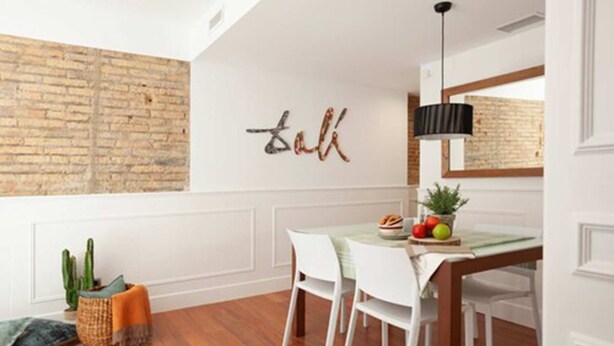 A dining area with a brick wall, a table with chairs, and a hanging light fixture. - Enjoybcn Dali Apartments (Barcelona)