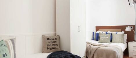 A modern bedroom with a bed, a wardrobe, and a nightstand.