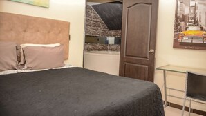 A bedroom with a bed, a door, a bathroom, and a poster on the wall.