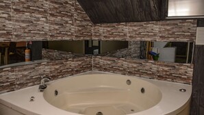 A bathroom with a freestanding bathtub, tiled walls, and a mirror.