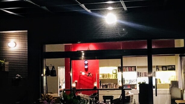 A modern building with a red facade, large windows, and a visible interior with bookshelves and furniture. - Read Nice House (Wujie)