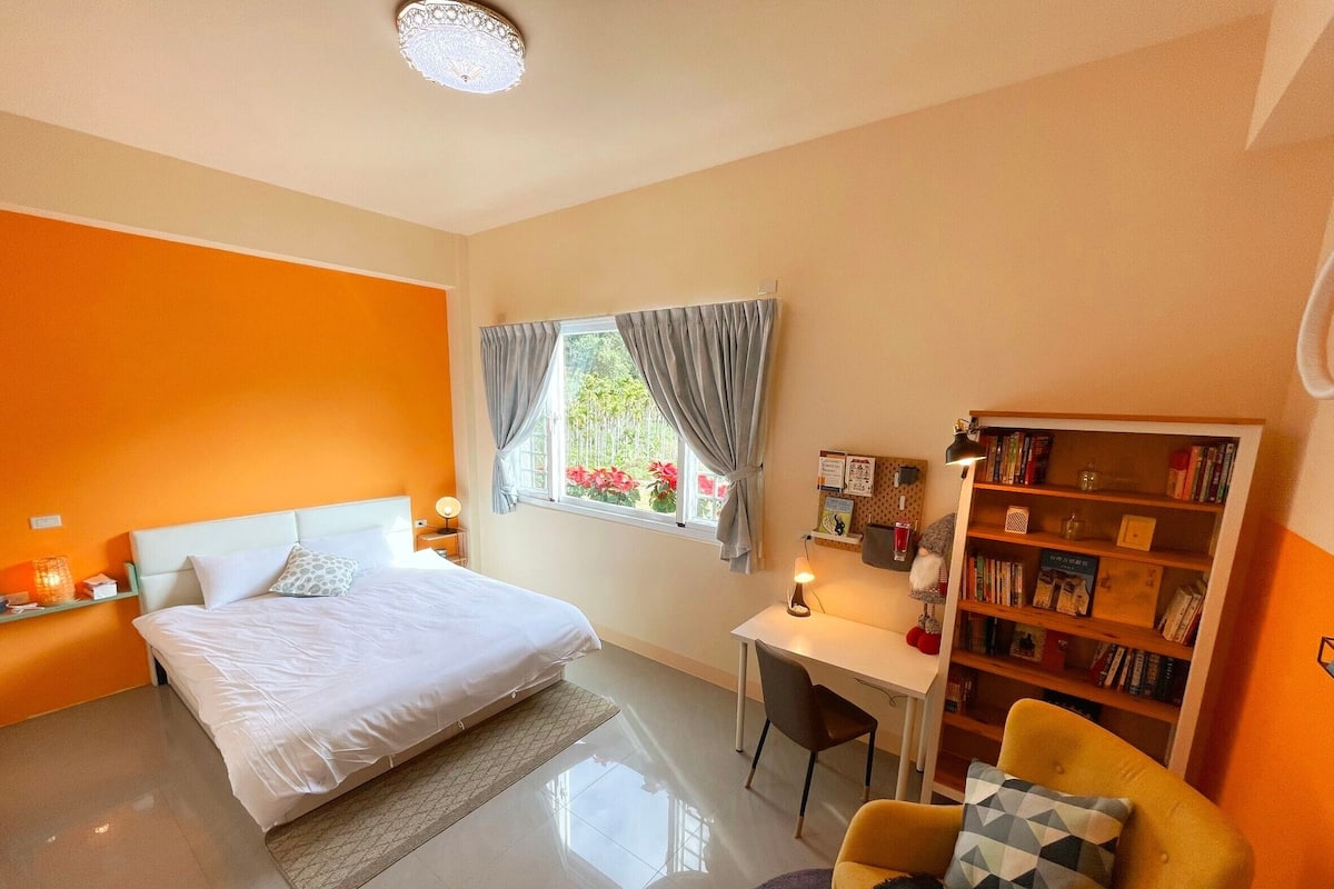 Een slaapkamer met een bed, bureau, stoel en een boekenkast.