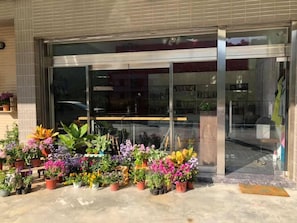 Welcome to a modern establishment with a beautiful entrance, surrounded by lush greenery.