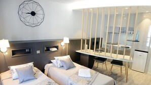 A hotel room with two beds, a desk, and a kitchenette. - La Residence des Thermes (Bagnères-de-Bigorre)