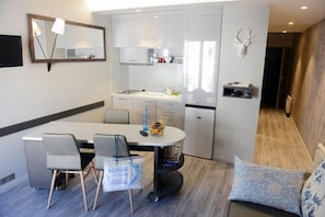 Une cuisine compacte avec un coin repas, un miroir et une décoration murale représentant une tête de cerf.