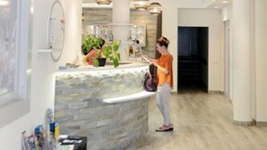 A reception area with a stone counter, hanging pendant lights, and a person standing near the counter. - La Residence des Thermes (Bagnères-de-Bigorre)