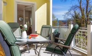 A balcony with a table, chairs, a potted plant, and a book.