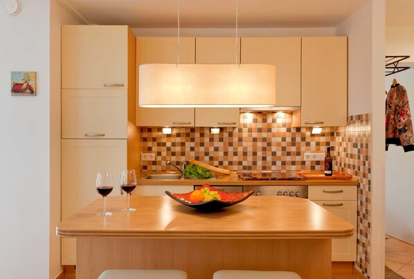 A modern kitchen with a central island, a hanging light fixture, and a tiled backsplash. - Holiday Apartment Mercedes in Zinnowitz (Zinnowitz)