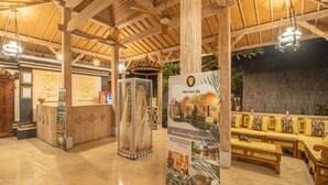 A lobby with wooden beams, a reception desk, a glass display case, and a seating area with a pool view. - Wana Shanti Villa (Mengwi)