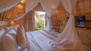 A bedroom with a canopy bed, wooden walls, and a television on a wooden cabinet. - Wana Shanti Villa (Mengwi)