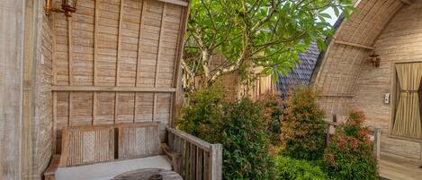 A wooden bench and table in a courtyard with a wooden wall and a tree.