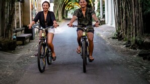 Two people riding bicycles on a tree-lined street. - Wana Shanti Villa (Mengwi)