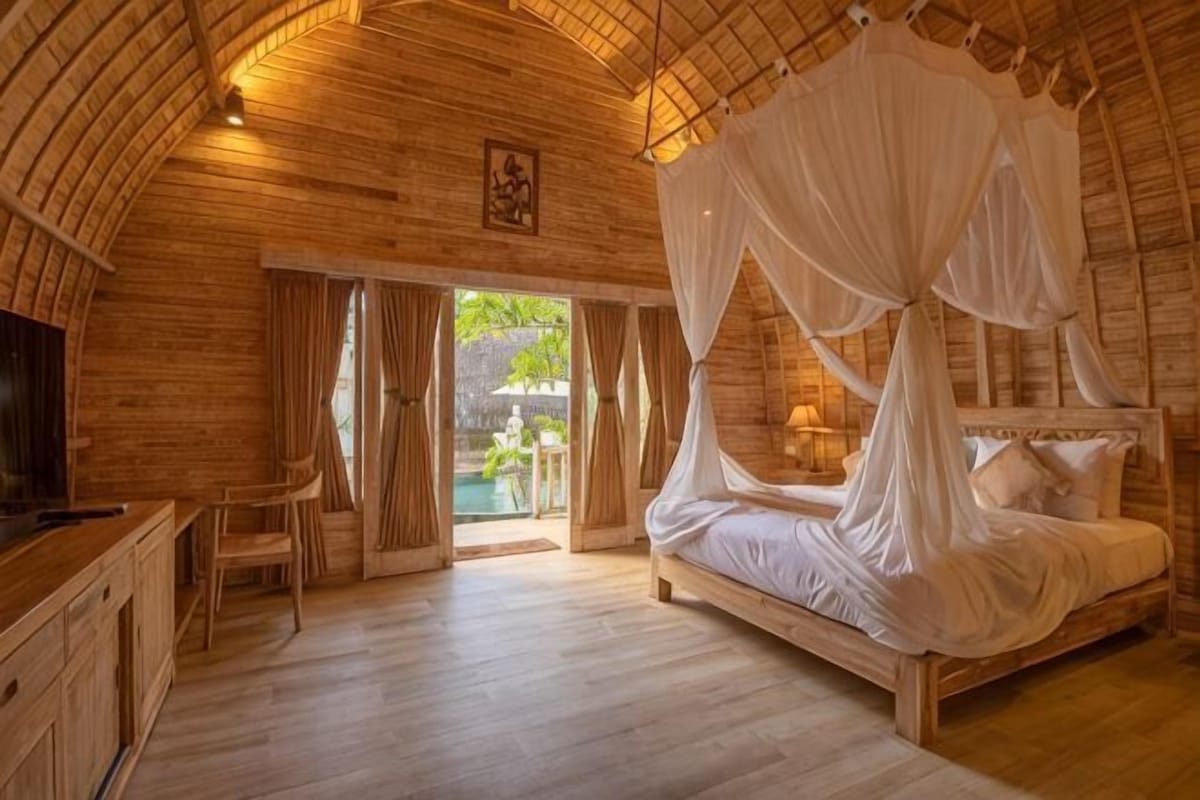 A wooden room with a bed, a desk, and a TV.