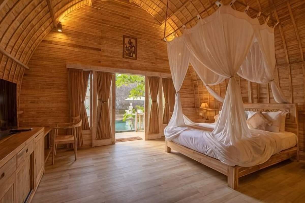 A wooden room with a bed, a desk, and a TV.