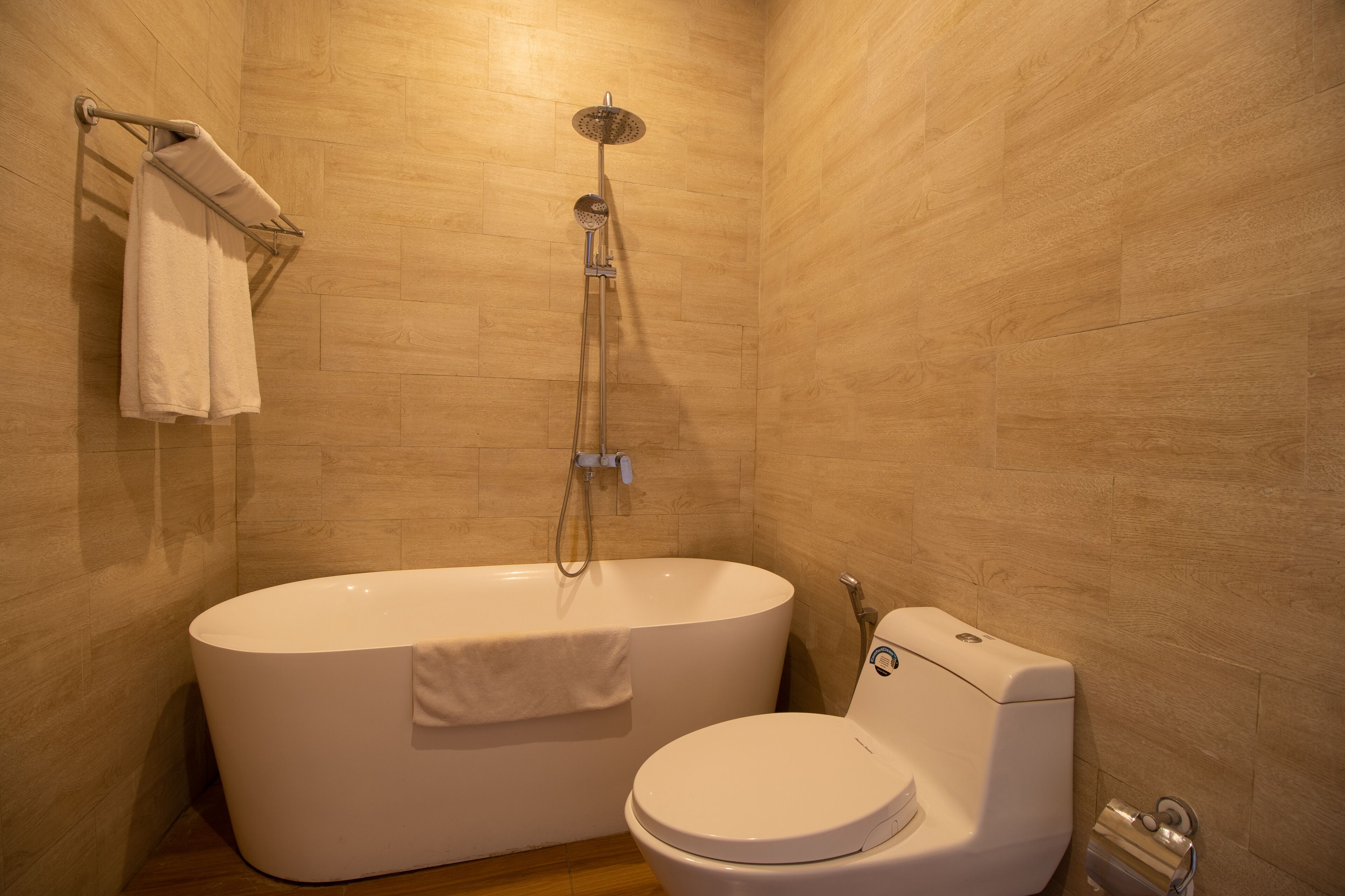 A bathroom with a freestanding bathtub, a toilet, and a towel rack.