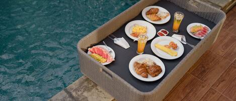A wicker tray with breakfast items by a pool.