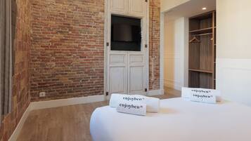 Habitación de hotel con pared de ladrillo, un armario blanco, un armario de madera y dos toallas con el texto "enjoyben".